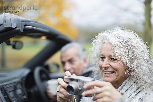Lächelndes Seniorenpaar mit Digitalkamera im Cabriolet