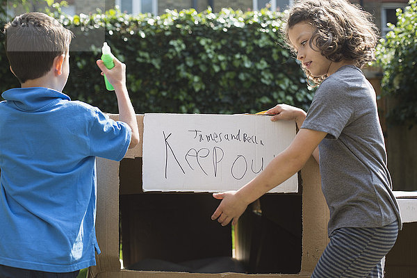 Elementare Freunde mit Schild auf Karton im Hinterhof