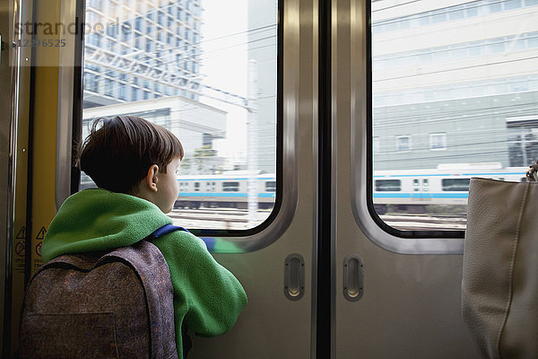 Rückansicht des Jungen,  der durch die geschlossene Tür schaut,  während er im Zug fährt