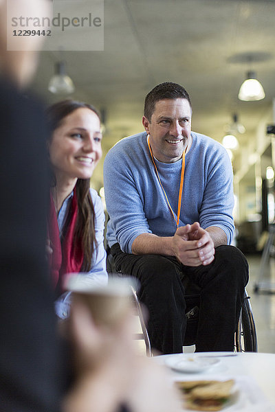 Smiling businessman in wheelchair networking,  talking with colleagues