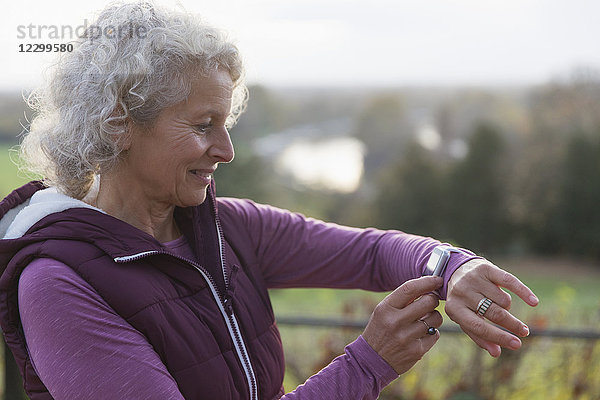 Active senior woman exercising,  using fitness tracker smart watch