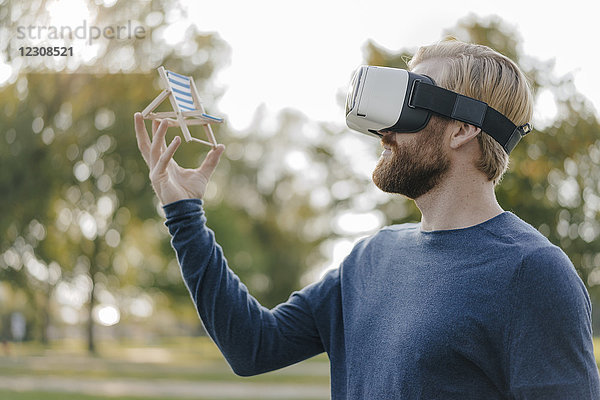Mann im herbstlichen Park mit Virtual Reality Brille auf Mini-Strandliege