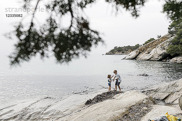 Greece,  Chalkidiki,  brother and little sister playing together on the beach