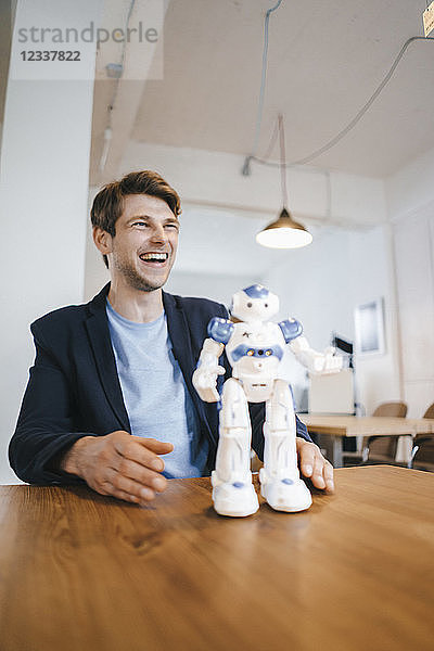 Laughing man with robot on table