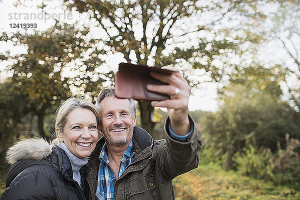 Glückliches reifes Paar nimmt Selfie mit Kamera-Handy im Herbst Wald