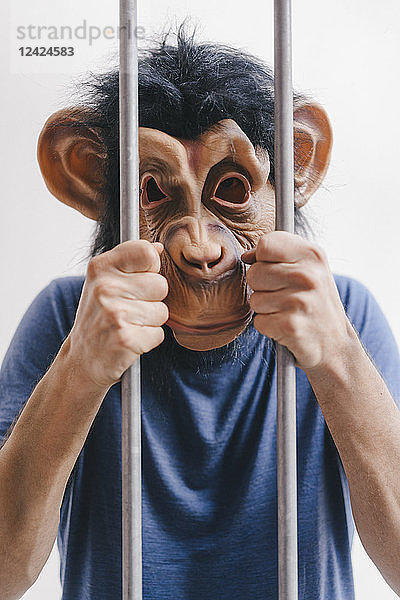 Man with monkey mask behind bars