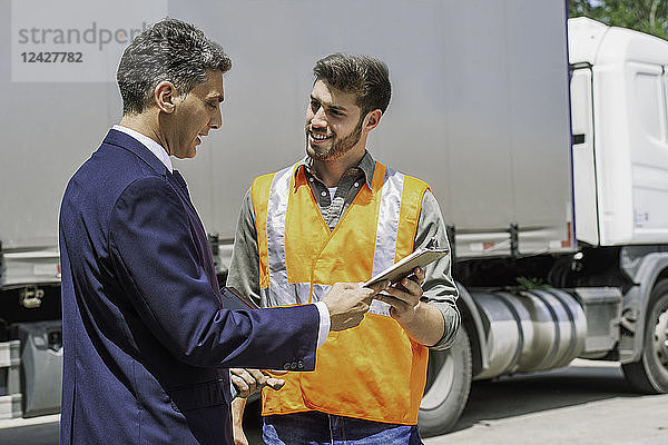 Arbeiter und Geschäftsmann diskutieren in der Nähe eines Lastwagens