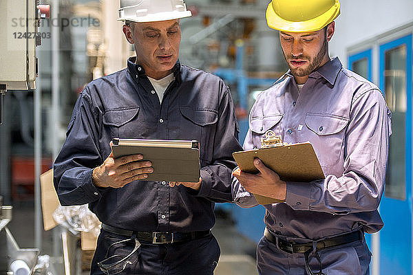 Fabrikarbeiter mit digitalem Tablet und Klemmbrett in einer Fabrik