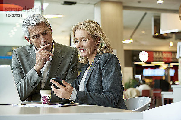Geschäftsleute benutzen ihr Smartphone in der Cafeteria