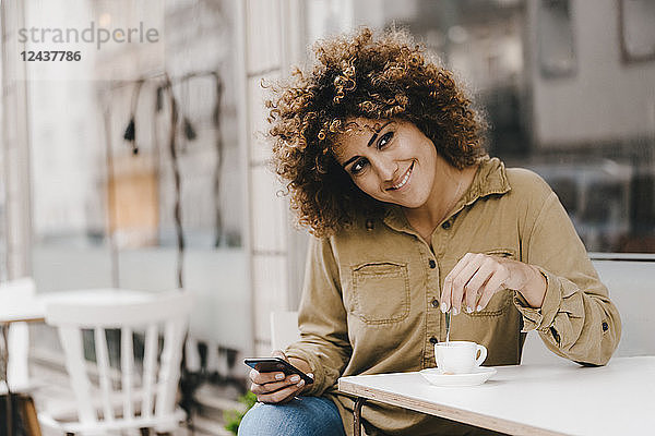 Woman in front of coffee shop,  drinking coffee,  holding smart phone
