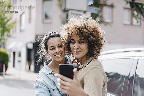 Best friends taking selfies with a smartphone in the city