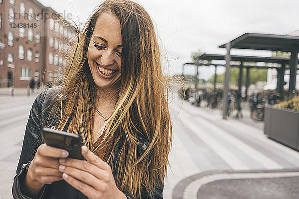 Happy young woman using cell phone in the city