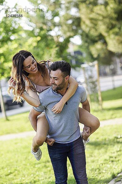 Happy man giving girlfriend a piggyback ride in park