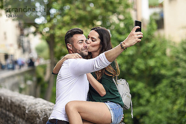 Couple in love in the city kissing and taking a selfie