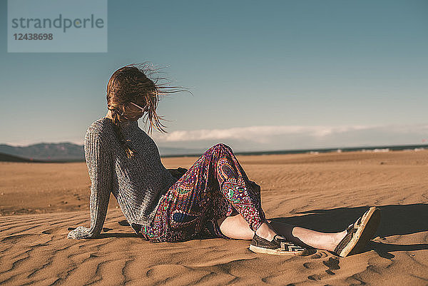 Spain,  fashinable young woman sitting on the beach