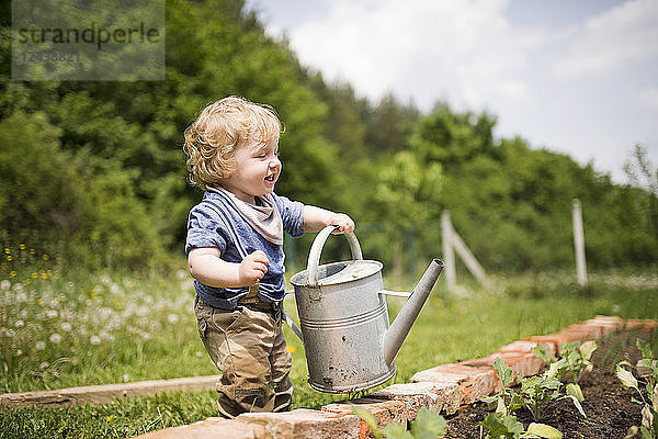 Little boy in the garden watering seedlings