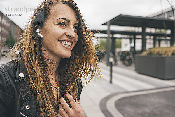 Smiling young woman wearing in-ear phones