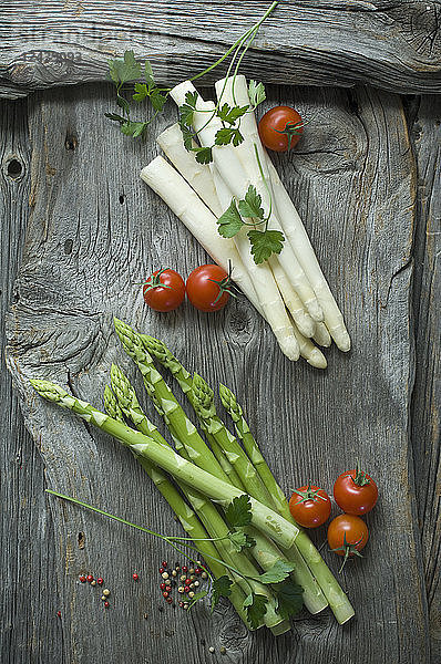 Green and white asparagus,  parsley,  tomatoes and mixed peppercorns on wood