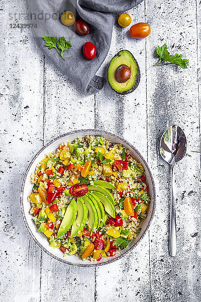 Bowl of bulgur salad with bell pepper,  tomatoes,  avocado,  spring onion and parsley