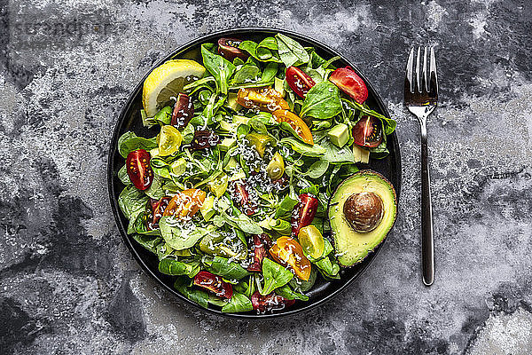 Salad with lamb's lettuce,  tomatoes,  avocado,  parmesan and curcuma lemon dressing