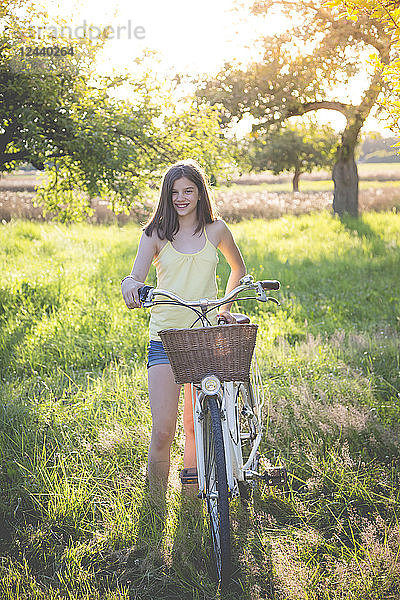 Portrait of smiling girl with bicycle in nature