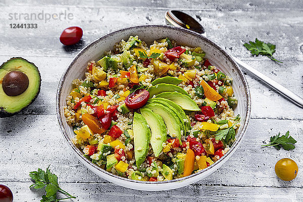 Bowl of bulgur salad with bell pepper,  tomatoes,  avocado,  spring onion and parsley