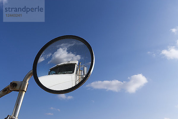 Ein Transport-LKW spiegelt sich im runden Seitenspiegel eines anderen LKW mit blauem Himmel,  Minnesota,  Vereinigte Staaten von Amerika