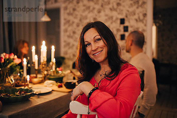 Portrait of smiling woman sitting with friends at dinner party