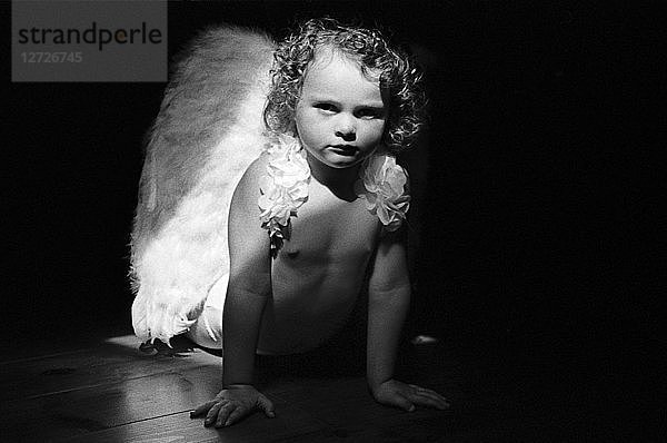 Schwarz-Weiß-Fotografie,  Büste eines kleinen Mädchens mit Engelsflügeln,  Innenlichteffekte
