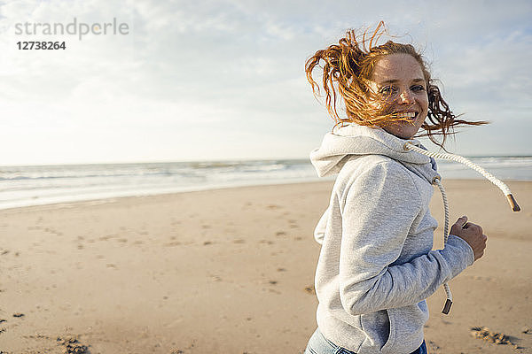 Redheaded woman running on the beach,  laughing