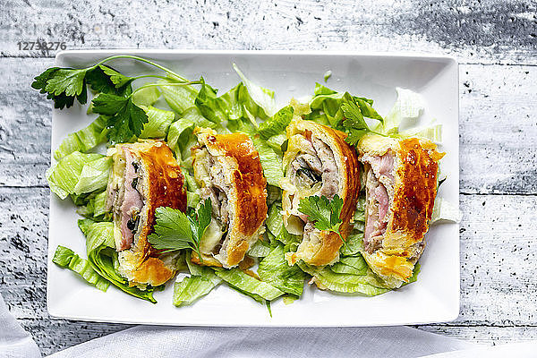 Swiss roll,  puff pastry with sausage meat,  cheese,  onion,  parsley and salad on plate