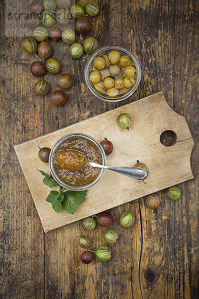 Jar of gooseberry jam,  gooseberries and glass of preseved gooseberries on wood