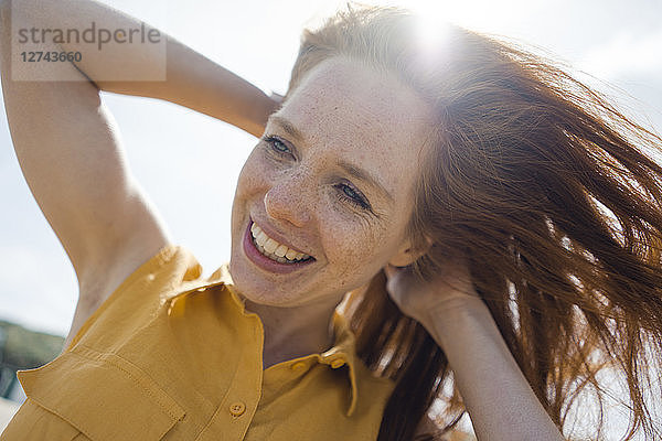 Portrait of a redheaded woman,  laughing happily on the beach