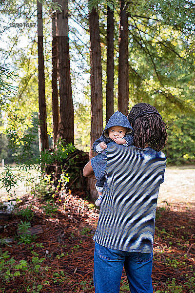 Erwachsener Mann trägt einen kleinen Sohn im Wald,  Porträt
