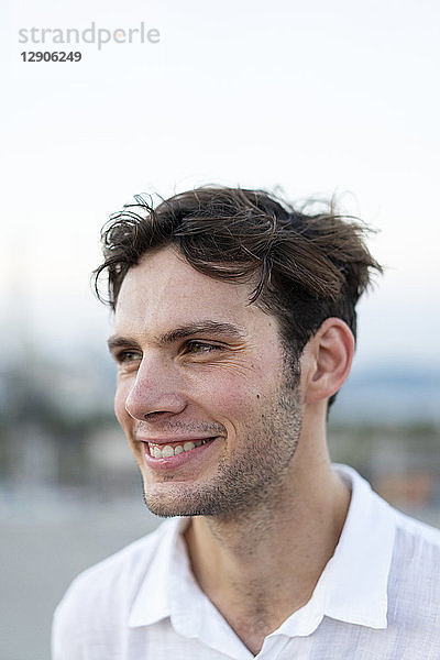 Portrait of smiling young man with tousled hair outdoors