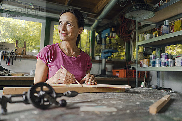 Smiling mature woman at workbench in her workshop
