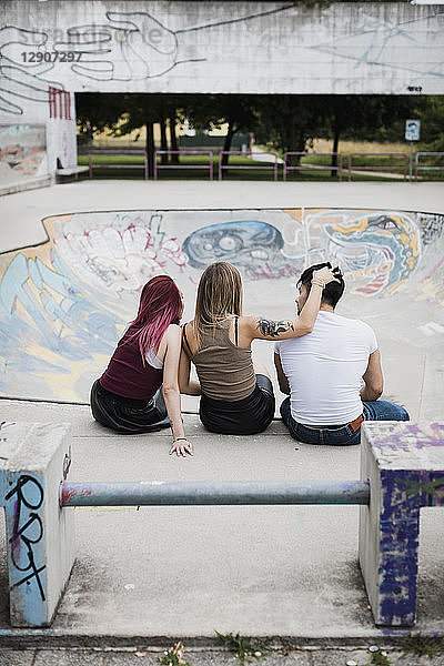 Rear view of friends sitting in skatepark