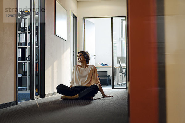 Businesswoman sitting cross-legged on floor in office