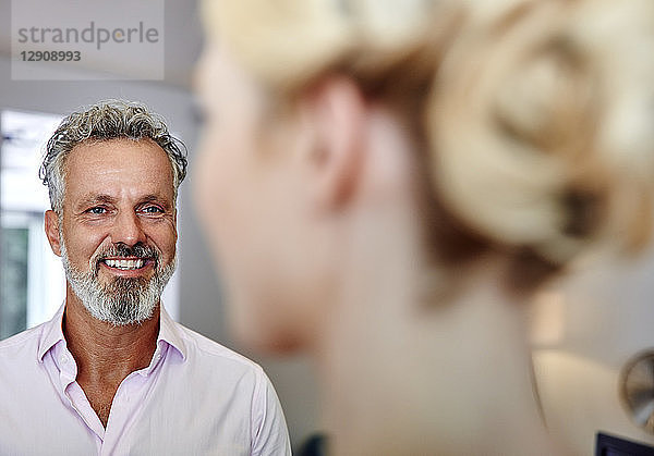 Smiling mature man looking at female colleague in office