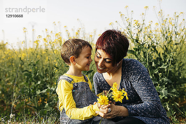 Mother and little son with picked flowers in a field