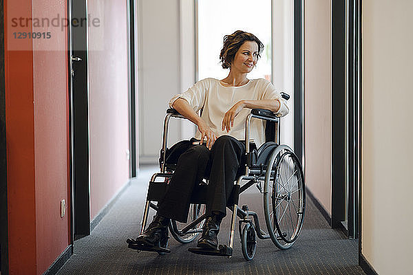 Disabled business woman sitting in wheelchair,  with laptop on knees