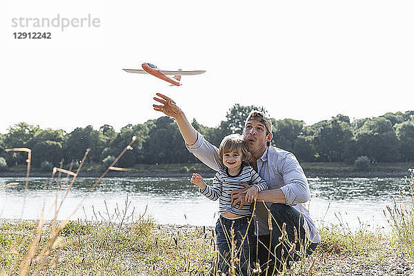 Father and son having fun at the riverside,  playing with toy aeroplane