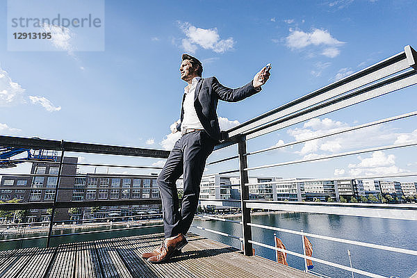 Happy businessman standing on balcony,  with arms out