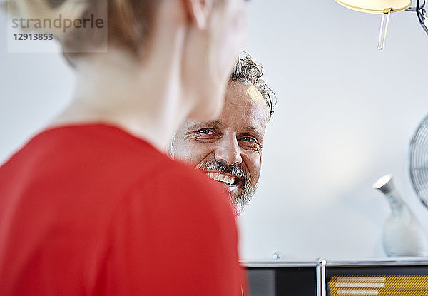 Smiling mature man looking at female colleague in office
