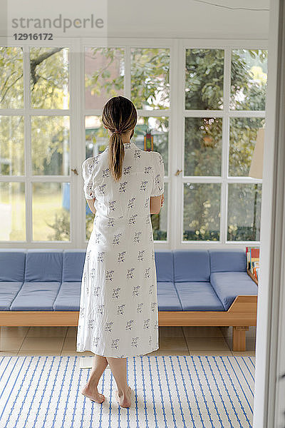 Rear view of woman standing in living room at home