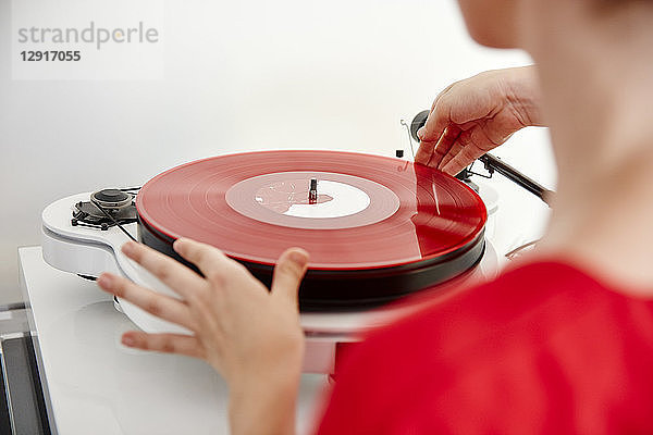 Woman putting red vinyl record on record player