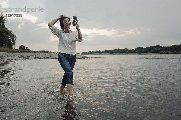 Laughing woman running at the riverside,  taking selfies