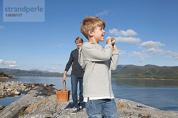 Junge und Vater tragen Korb über den Einlassfelsen,  Aure,  More og Romsdal,  Norwegen
