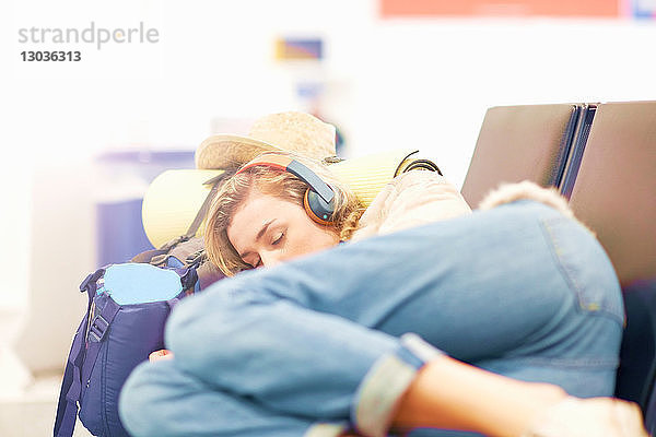 Junge Frau am Flughafen,  schläft auf einem Sitzplatz in der Abflughalle