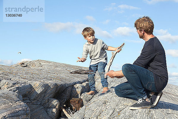 Junge und Vater bereiten ein Lagerfeuer auf dem Einlassfelsen vor,  Aure,  More og Romsdal,  Norwegen